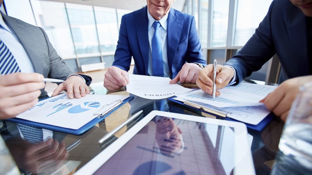 Businessmen sitting at table and examining reports